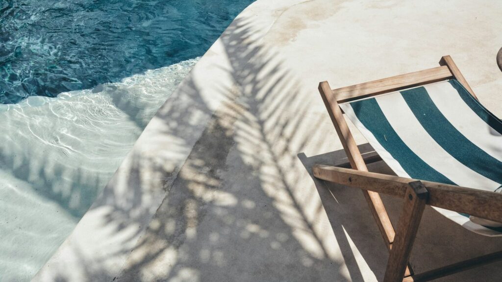 brown wooden lounger near body of water